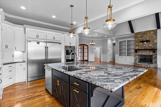 kitchen with pendant lighting, light wood-type flooring, white cabinetry, and appliances with stainless steel finishes