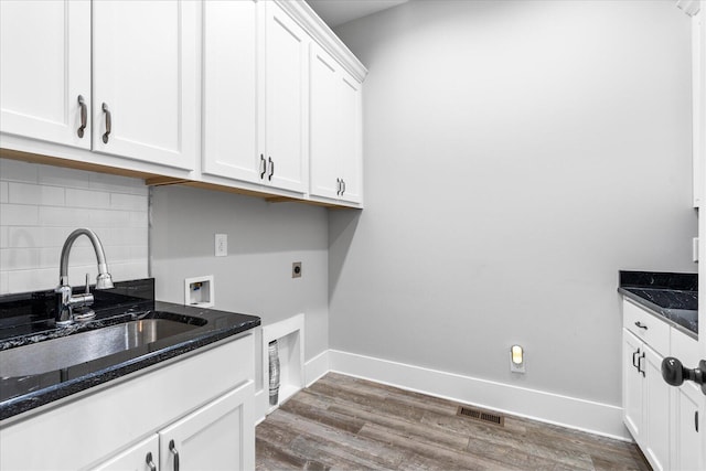 clothes washing area featuring cabinets, washer hookup, hookup for an electric dryer, sink, and dark hardwood / wood-style floors