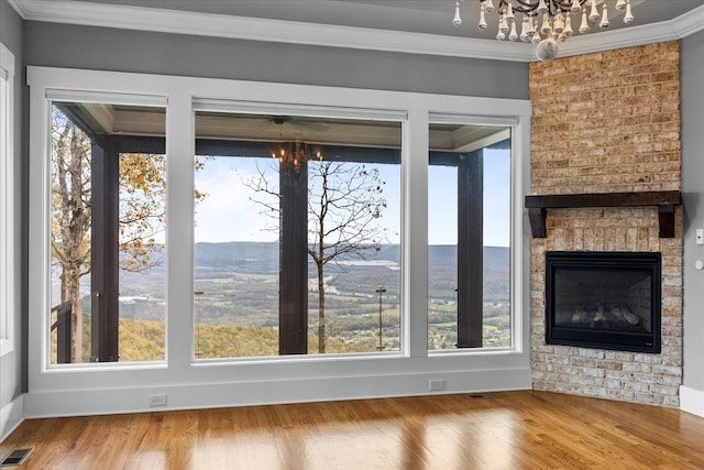 unfurnished living room with a mountain view, hardwood / wood-style floors, a wealth of natural light, and crown molding