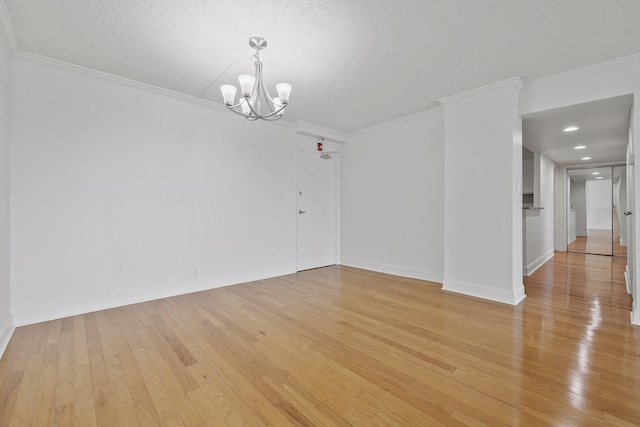 empty room featuring ornamental molding, a chandelier, a textured ceiling, and light hardwood / wood-style floors