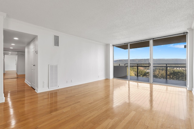 spare room with crown molding, light hardwood / wood-style floors, and floor to ceiling windows