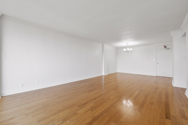 empty room featuring ornamental molding, light hardwood / wood-style flooring, a textured ceiling, and a chandelier