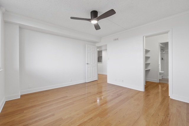 unfurnished bedroom with a spacious closet, light hardwood / wood-style flooring, a textured ceiling, and ceiling fan