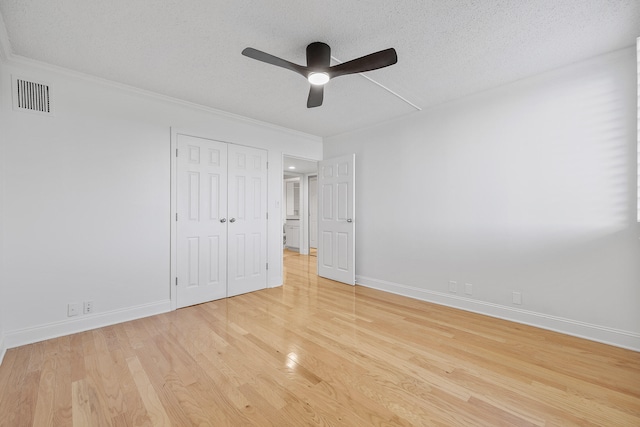 unfurnished bedroom featuring a closet, a textured ceiling, light wood-type flooring, and ceiling fan