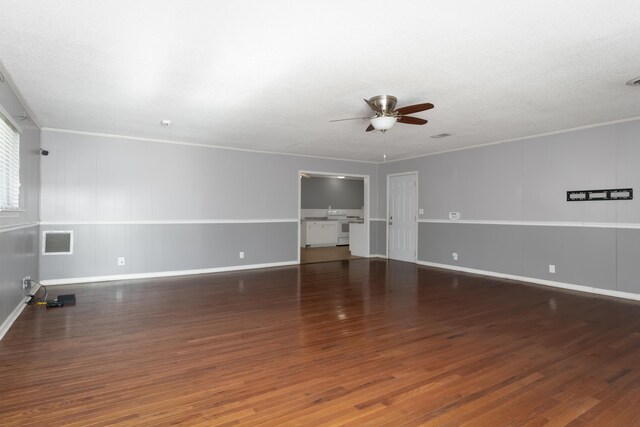 empty room with ornamental molding, a textured ceiling, dark wood-type flooring, and ceiling fan