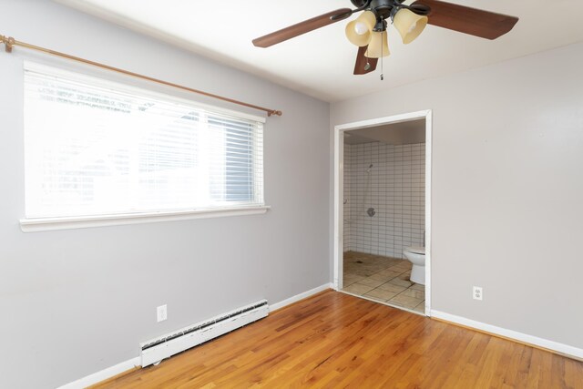 unfurnished bedroom featuring hardwood / wood-style floors, ensuite bathroom, a baseboard radiator, and ceiling fan