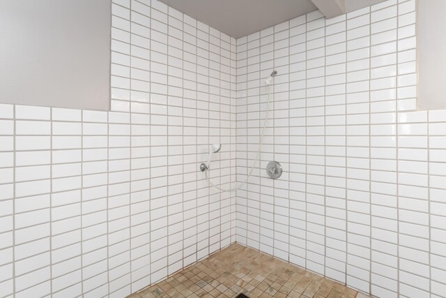 bathroom featuring a tile shower and tile walls