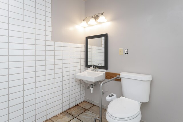 bathroom featuring toilet, sink, tile patterned floors, and tile walls