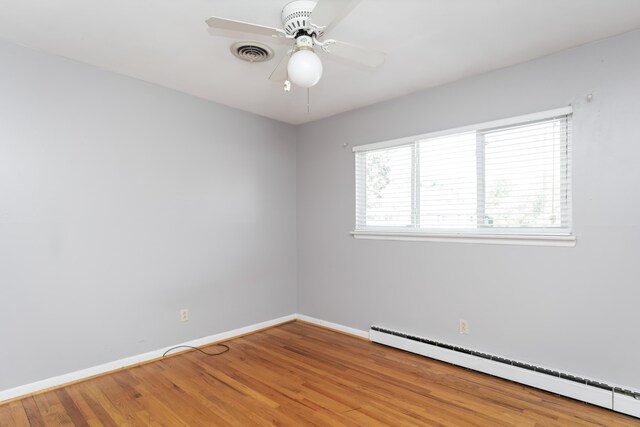 spare room with ceiling fan, baseboard heating, and hardwood / wood-style floors