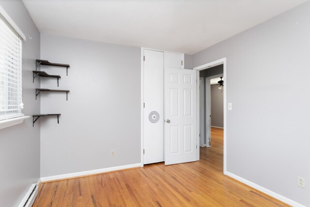 empty room featuring light wood-type flooring, a baseboard heating unit, plenty of natural light, and ceiling fan