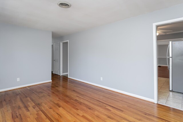 unfurnished bedroom featuring light hardwood / wood-style flooring and stainless steel fridge