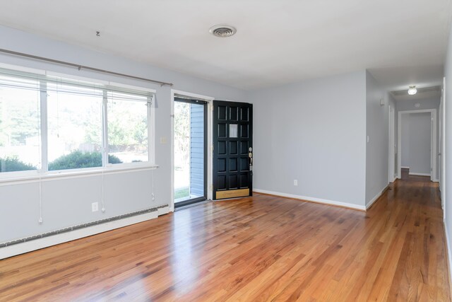 unfurnished room with a baseboard radiator and light wood-type flooring