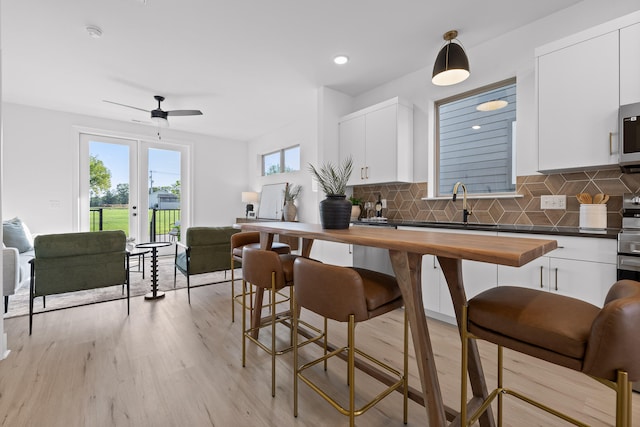 kitchen with white cabinetry, wooden counters, light hardwood / wood-style flooring, and hanging light fixtures