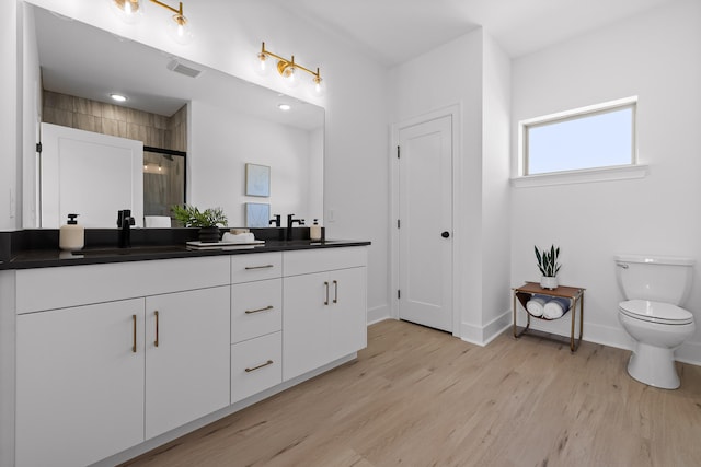 bathroom featuring walk in shower, wood-type flooring, toilet, and vanity