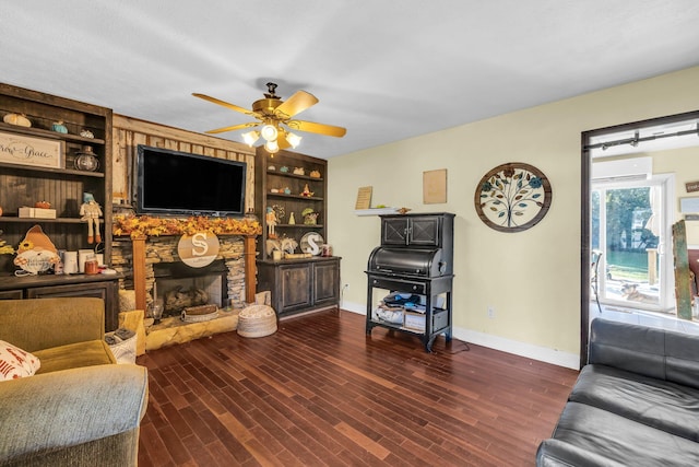 living room with ceiling fan, a wall mounted air conditioner, dark wood-type flooring, built in features, and a fireplace