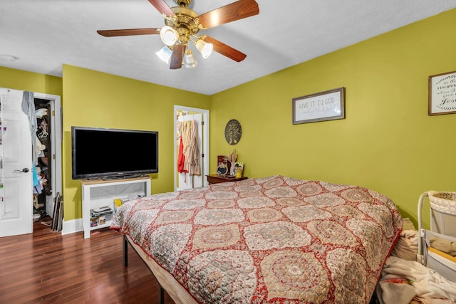 bedroom with dark hardwood / wood-style floors, a closet, a walk in closet, ensuite bath, and ceiling fan