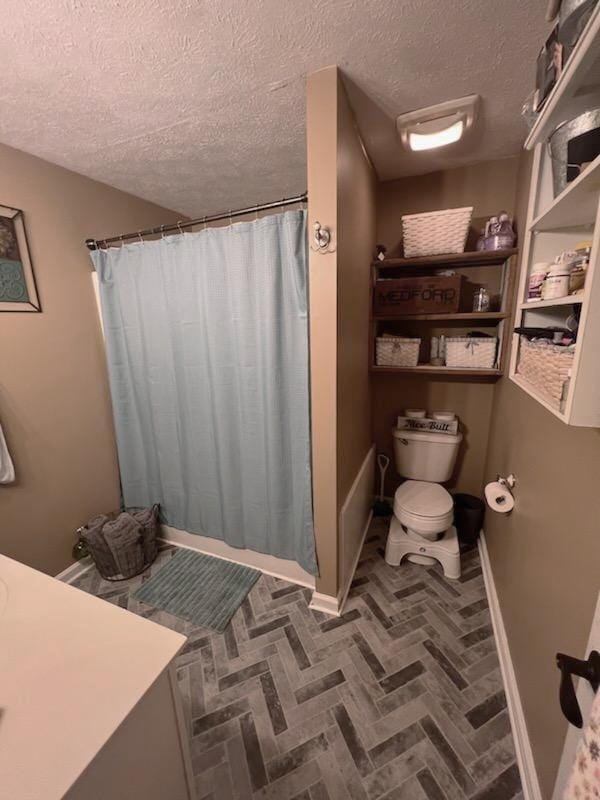 bathroom with toilet, a textured ceiling, walk in shower, and vanity