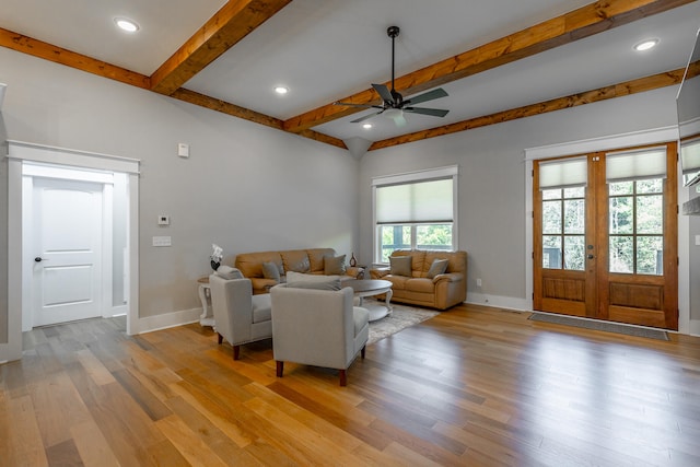 living room featuring ceiling fan, beamed ceiling, a wealth of natural light, and light wood-type flooring