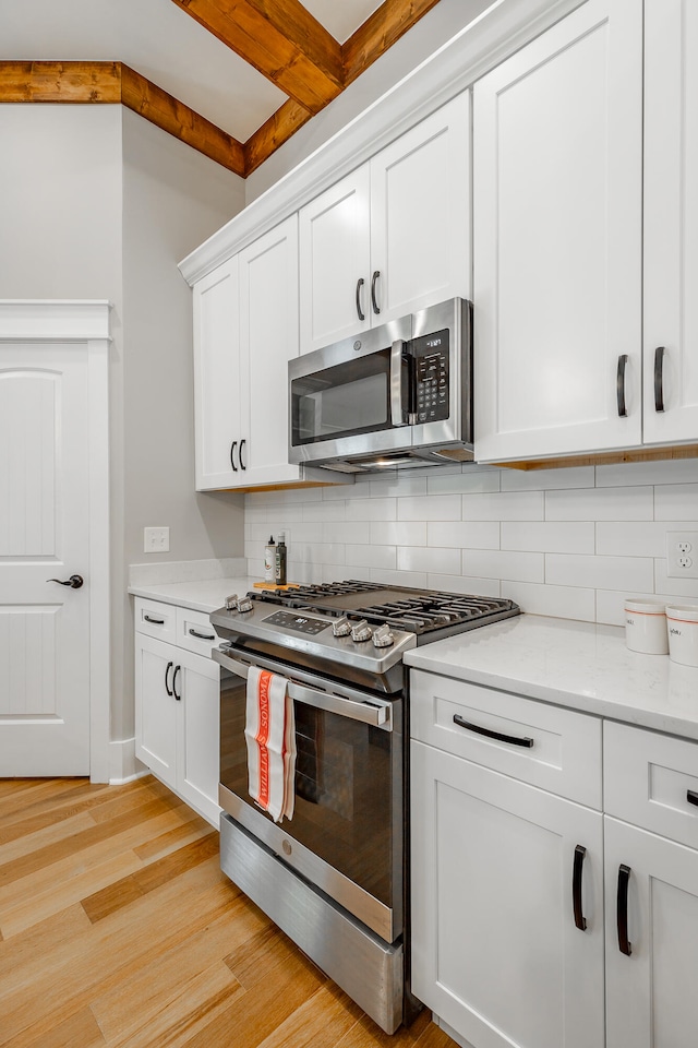 kitchen featuring white cabinets, light hardwood / wood-style flooring, stainless steel appliances, and tasteful backsplash