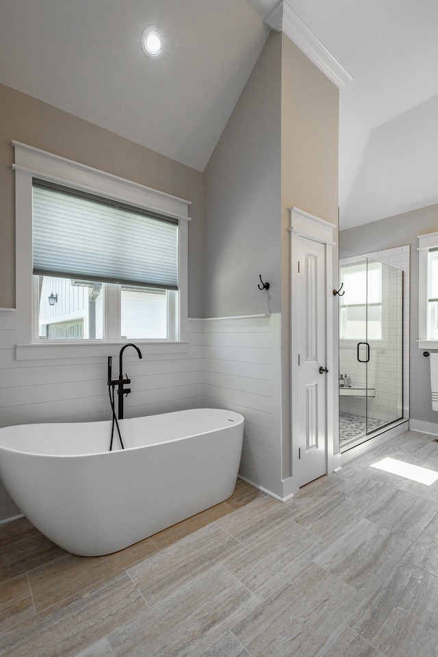 bathroom featuring plus walk in shower, a wealth of natural light, wood-type flooring, and vaulted ceiling