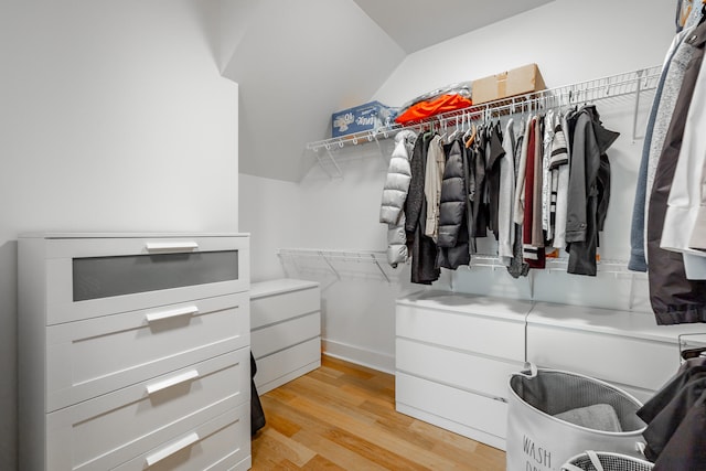 walk in closet with light hardwood / wood-style floors and lofted ceiling