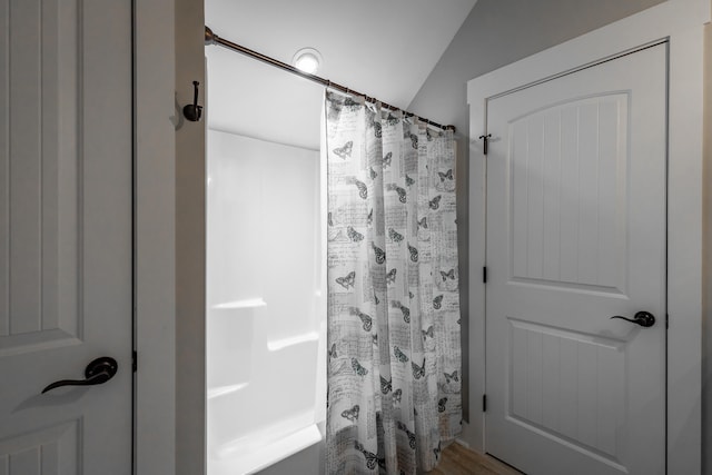 bathroom featuring vaulted ceiling, hardwood / wood-style flooring, and walk in shower