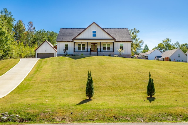 modern farmhouse featuring a front yard, a garage, and an outbuilding