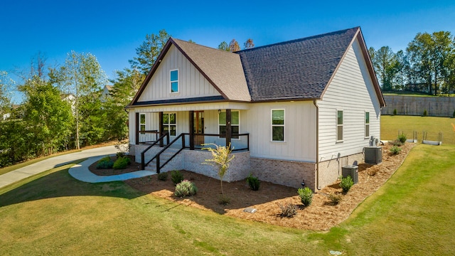 view of front of property featuring a front yard, covered porch, and central AC unit