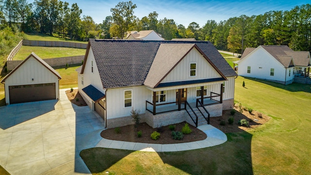 modern inspired farmhouse featuring a front yard, a garage, a porch, and an outdoor structure