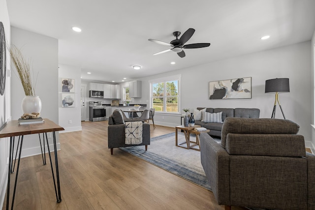 living room featuring ceiling fan and light hardwood / wood-style flooring