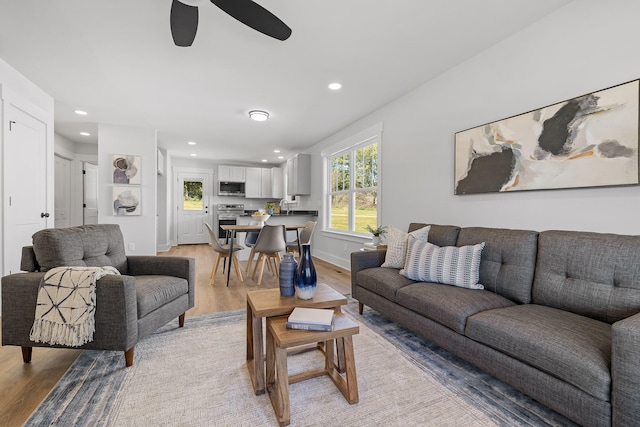 living room with ceiling fan and light hardwood / wood-style flooring