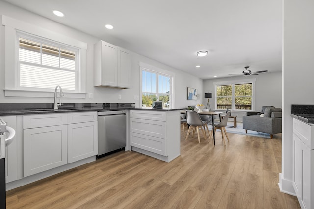 kitchen featuring stainless steel dishwasher, white cabinets, light wood-type flooring, and plenty of natural light