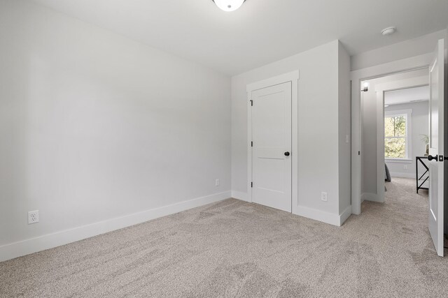 unfurnished bedroom with a closet and light colored carpet