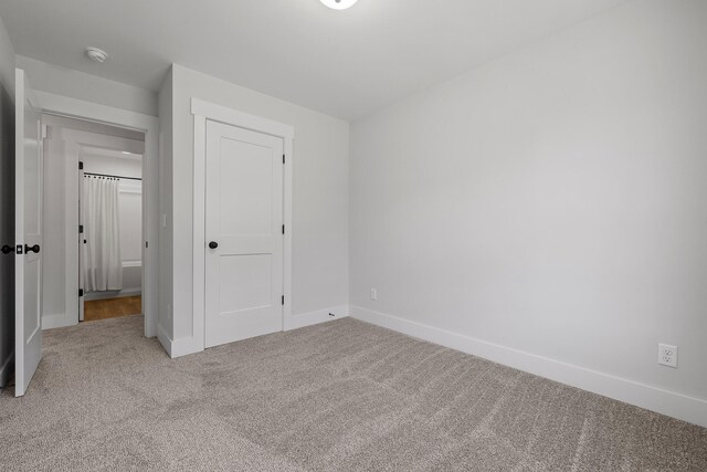 unfurnished bedroom with light colored carpet and a closet