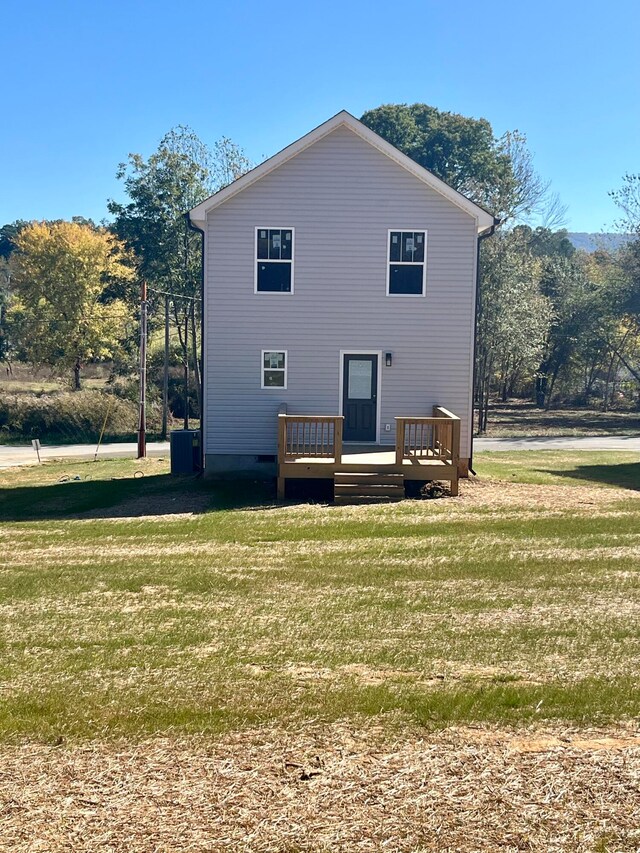 rear view of property featuring a deck and a lawn