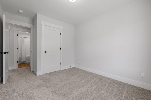 unfurnished bedroom featuring a closet and light colored carpet