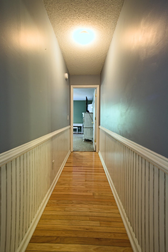 hallway with hardwood / wood-style floors and a textured ceiling