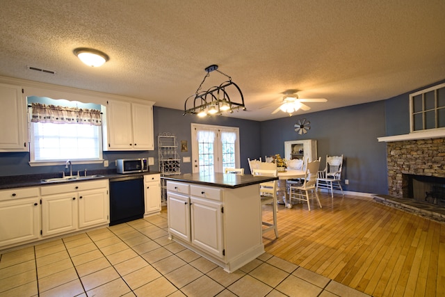 kitchen featuring dishwasher, a center island, white cabinets, a kitchen breakfast bar, and a fireplace