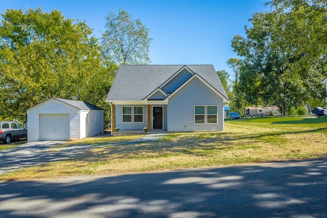 view of front of property featuring a garage, a front lawn, and an outbuilding