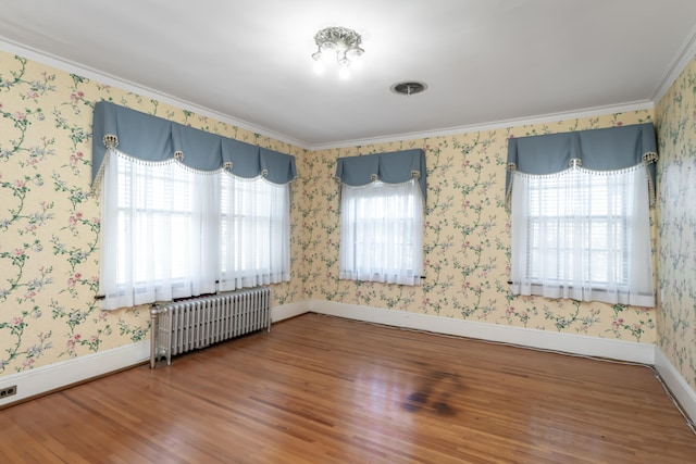 unfurnished room featuring wood-type flooring, crown molding, and radiator