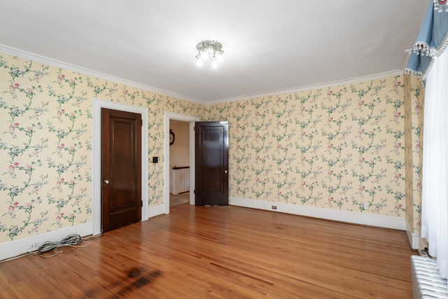 spare room with hardwood / wood-style floors, radiator, and crown molding