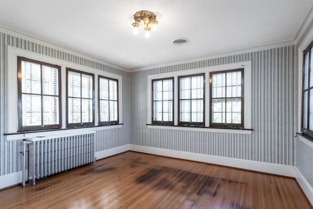 unfurnished room featuring wood-type flooring and ornamental molding