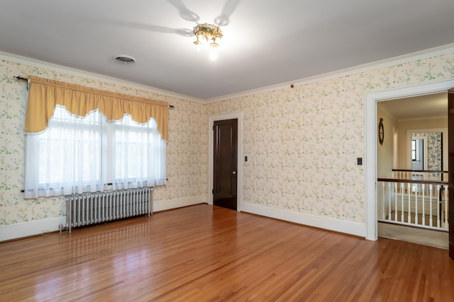 unfurnished room with crown molding, radiator heating unit, and hardwood / wood-style floors