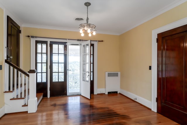 entrance foyer with radiator, french doors, crown molding, a chandelier, and hardwood / wood-style flooring