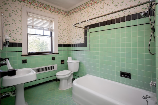 bathroom featuring toilet, tiled shower / bath, and tile walls