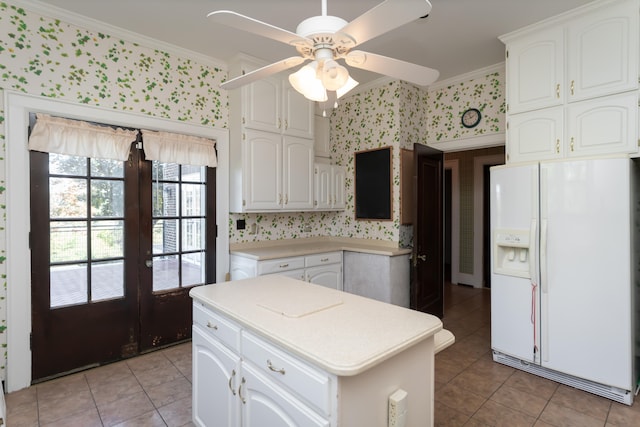 kitchen featuring white refrigerator with ice dispenser, white cabinets, and ornamental molding