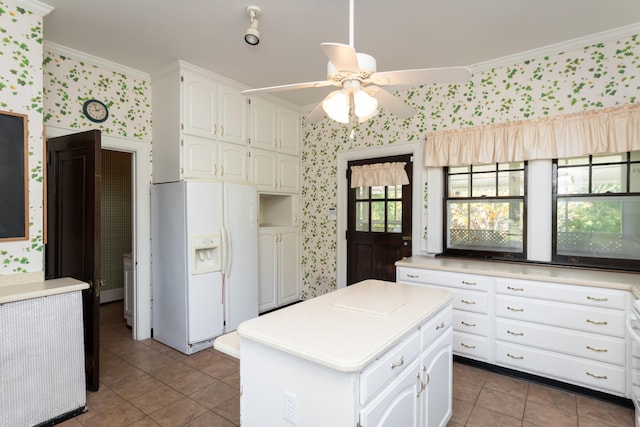 kitchen with white cabinets, ceiling fan, white fridge with ice dispenser, ornamental molding, and a kitchen island