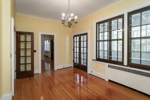 doorway to outside with radiator, french doors, an inviting chandelier, hardwood / wood-style flooring, and ornamental molding