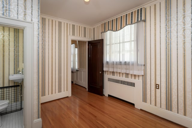 unfurnished room with radiator, wood-type flooring, and ornamental molding