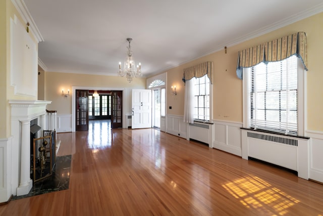 unfurnished living room with radiator, crown molding, a high end fireplace, and hardwood / wood-style flooring